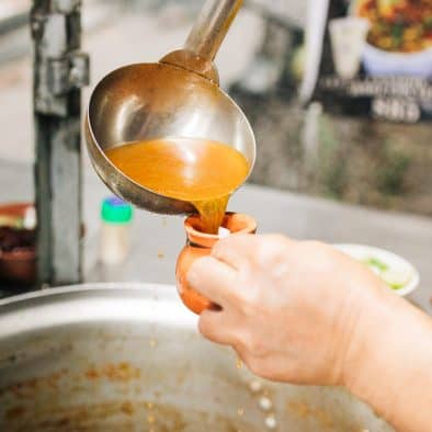 Hand serving hot sopa de fideo in Juarez food tour experience.