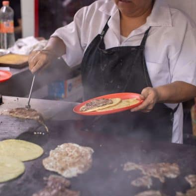 Chef cooking traditional tacos on a hot griddle.