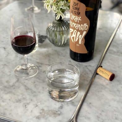 Wine bottle, glass of red wine, and street food setting at a food tour.