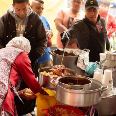 Bustling Central de Abastos food market with vendors serving traditional Mexican dishes to eager cus.
