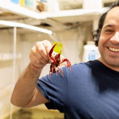 Man holding a fresh lobster at Central de Abastos food market in Mexico City.