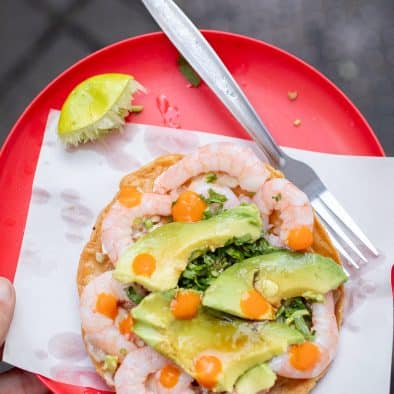 Delicious shrimp and avocado tostada topped with orange roe, served on a vibrant red plate for an au.
